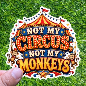 May include: A colorful sticker with a circus theme. The sticker features the text "NOT MY CIRCUS, NOT MY MONKEYS" in bold, illuminated letters. Two cartoon monkeys are holding onto ropes. The design includes red, blue, yellow, and white elements.