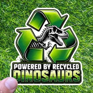 May include: A sticker featuring a green recycling symbol with a black and white dinosaur skeleton inside. The text "POWERED BY RECYCLED DINOSAURS" is displayed below the symbol in a green and yellow font.