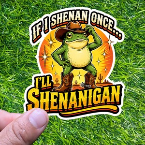 May include: A sticker featuring a cartoon frog wearing a cowboy hat and boots, with the text "If I Shenan Once... I'll Shenanigan". The frog is green with a yellow belly, set against an orange sunset background.