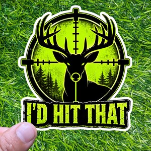 Puede incluir: Una pegatina con la silueta negra de un ciervo dentro de una mira de color verde neón. El texto "I'D HIT THAT" está en amarillo. El diseño incluye una escena de bosque. La pegatina está sobre un fondo verde.