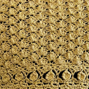 May include: Gold crochet fabric with a textured, raised pattern. The fabric has a shiny, metallic finish.