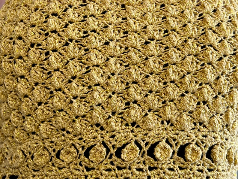May include: Gold crochet fabric with a textured, raised pattern. The fabric has a shiny, metallic finish.