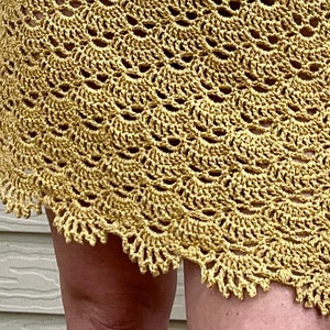 May include: A crocheted skirt in a light yellow color with a scalloped hem.