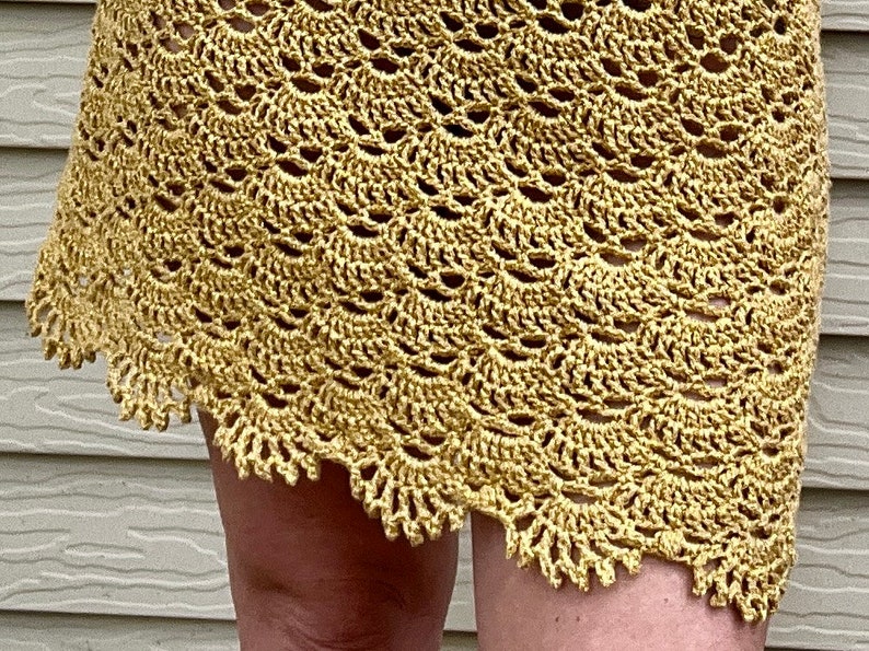 May include: A crocheted skirt in a light yellow color with a scalloped hem.