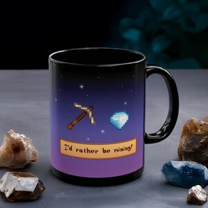 May include: Black coffee mug with a purple and blue galaxy design. The mug has a white border with the text "I'd rather be mining!" and a pixelated pickaxe and diamond.