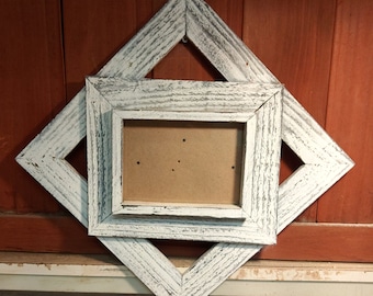 May include: Whitewashed wooden picture frame with a diamond shape. The frame is made of two layers of wood, creating a double frame effect.