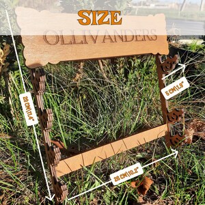 Puede incluir: Se&ntilde;al de madera con el texto "Ollivanders" y la palabra "SIZE" encima. La se&ntilde;al mide 28 cm de ancho y 5 cm de alto. La se&ntilde;al est&aacute; sobre una superficie de hierba verde.