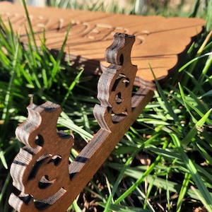 Puede incluir: Primer plano de un letrero de madera con la palabra "ORDERS" tallada en &eacute;l. El letrero tiene un dise&ntilde;o decorativo con dos figuras estilizadas en la parte inferior.