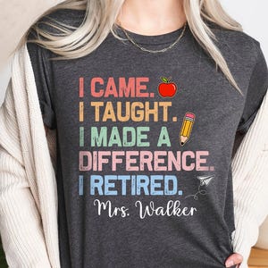 May include: Heather dark grey t-shirt with a colorful graphic that reads "I came. I taught. I made a difference. I retired. Mrs. Walker".