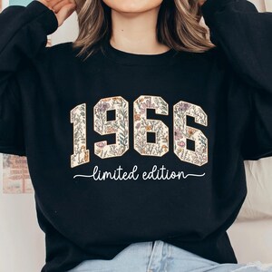 May include: Black sweatshirt with the year "1966" in a floral design. The words "limited edition" are written below the year in a cursive font. The sweatshirt is a crew neck style.