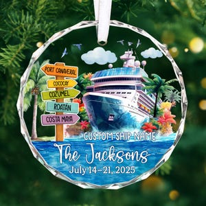 May include: A round, clear ornament with a cruise ship design. The ornament features a cruise ship on blue water, palm trees, and a signpost with destinations. Text includes "The Jacksons" and "July 14-21, 2025."