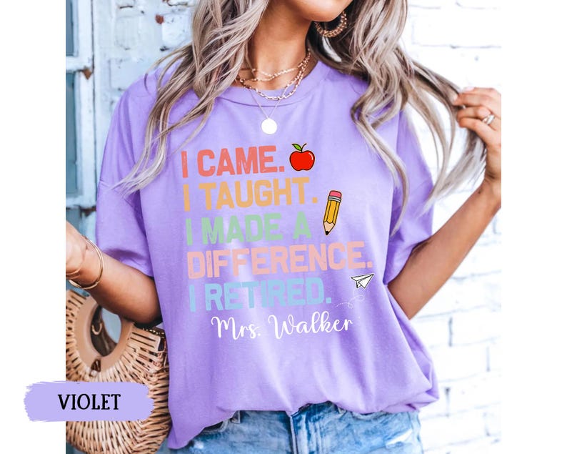 May include: Purple t-shirt with the text "I came. I taught. I made a difference. I retired. Mrs. Walker" in rainbow colors with a red apple, pencil, and paper airplane graphic.