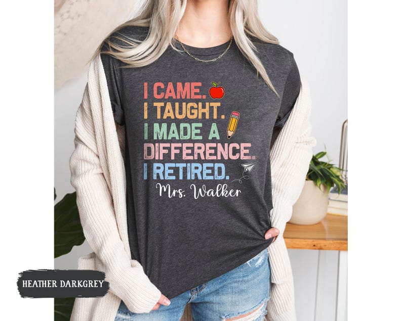 May include: Heather dark grey t-shirt with a colorful graphic that reads "I came. I taught. I made a difference. I retired. Mrs. Walker".