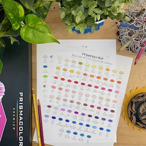 Może przedstawiać: Tabela kolorów dla ołówków kolorowych Prismacolor Premier. Tabela przedstawia 150 różnych kolorów, z których każdy jest reprezentowany przez małe kółko. Kolory są ułożone w rzędach, a kolory w każdym rzędzie stopniowo zmieniają się od jasnych do ciemnych. Tabela jest wydrukowana na białym arkuszu papieru.