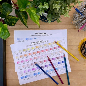 Może przedstawiać: Dwa arkusze papieru z wzornikami kolorów dla ołówków kolorowych Prismacolor 132-kolorowych. Arkusze są oznaczone "132-Count Gradient Swatch Sheet 1/2" i "132-Count Gradient Swatch Sheet 2/2". Pięć kolorowych ołówków leży na arkuszach.