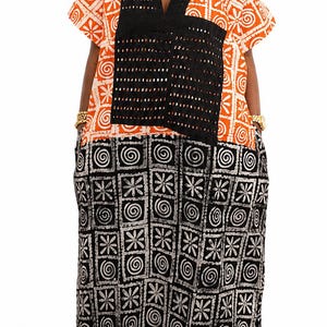 May include: A floor-length dress featuring a vibrant orange and white patterned upper section and a black and white patterned lower section. The garment includes a black, perforated V-neck panel and short sleeves, creating a distinct contrast.