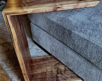 May include: A dark brown wooden side table with a unique curved design. The table has a natural wood finish and a smooth surface.