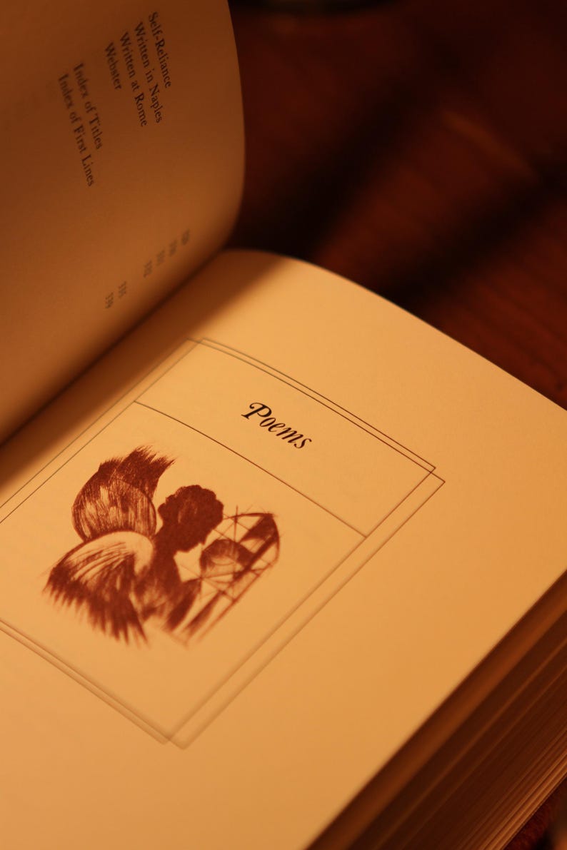 May include: Open book with the title "Poems" on the page. The page features a sepia-toned illustration of an angel with wings and a stained-glass window. The book's index is visible, with titles like "Self-Reliance" and "Index of Titles".
