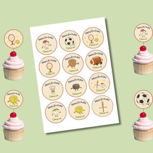 May include: A sheet of round stickers with sports-themed illustrations and the text "Happy Birthday Cameron." Cupcakes with pink frosting and a cherry are topped with matching sports-themed toppers. The background is light green.