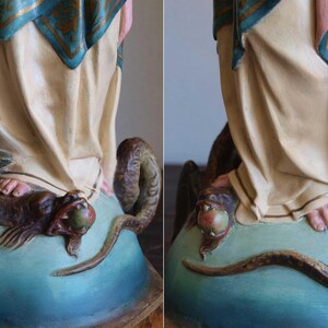 K&ouml;nnte beinhalten: Detaillierte Ansicht einer religi&ouml;sen Statue, die eine Figur in flie&szlig;enden Gew&auml;ndern darstellt, die auf einer Schlange und einem gefl&uuml;gelten Wesen steht. Die Statue hat einen hellblauen Sockel, wobei die F&uuml;&szlig;e der Figur und der K&ouml;rper der Schlange sichtbar sind.