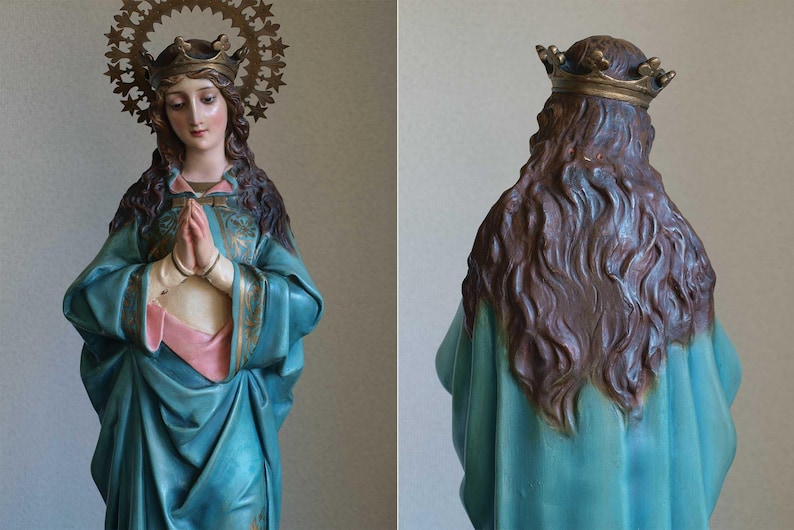 K&ouml;nnte beinhalten: Vintage Statue einer Frau mit Krone und Heiligenschein, die ein tealfarbenes Gewand mit rosa und goldenen Akzenten tr&auml;gt. Die Statue hat lange braune Haare und betet. Der Heiligenschein ist aus goldfarbenem Metall.