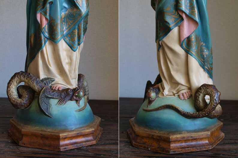 K&ouml;nnte beinhalten: Vintage Statue, die eine Figur in flie&szlig;enden Gew&auml;ndern darstellt, mit einem Schal mit t&uuml;rkisfarbenem und goldenem Muster. Die Statue steht auf einem Sockel mit einer sich darum windenden Schlange. Der Sockel ist in Blau- und Braunt&ouml;nen bemalt.