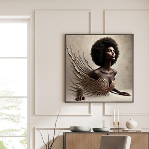 May include: A framed art print showing a woman with dark skin and a large afro. The artwork depicts a figure emerging from a textured, layered design in beige and gold tones. The image is displayed on a wall in a room with neutral colours.