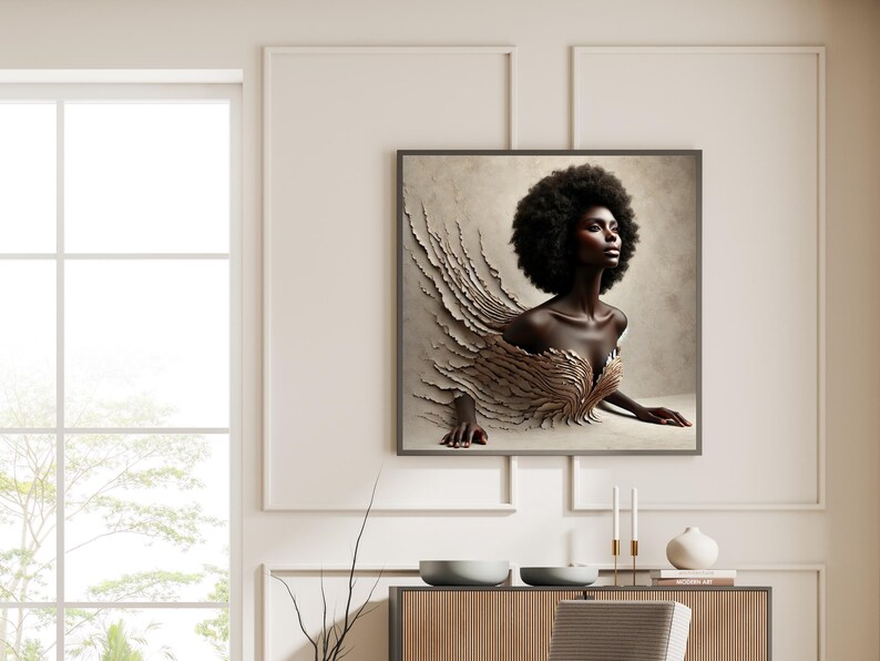 May include: A framed art print showing a woman with dark skin and a large afro. The artwork depicts a figure emerging from a textured, layered design in beige and gold tones. The image is displayed on a wall in a room with neutral colours.