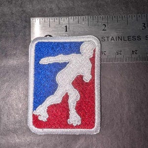 May include: A white embroidered patch with a red and blue background. The patch features a white silhouette of a person roller skating. The patch is approximately 1.5 inches wide and 2 inches tall.