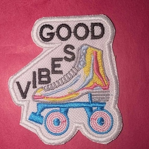 Op de afbeelding: Witte geborduurde patch met een rolstoel en de tekst "GOOD VIBES".