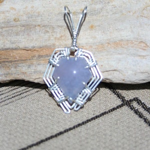 May include: A silver wire wrapped pendant featuring a light purple heart-shaped gemstone.
