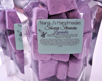 May include: A clear plastic bag filled with lavender-scented shower steamers. The bag has a label that reads "Nana J's Handmades Shower Steamers Lavender". The label also includes the ingredients and directions for use.