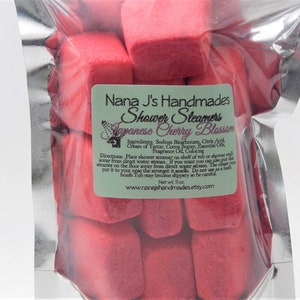 May include: A bag of red shower steamers with the label "Nana J's Handmades Shower Steamers Japanese Cherry Blossom". The label also includes the ingredients and directions for use. Net wt. 11 oz.