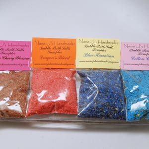 May include: Four small bags of bubble bath salts, each with a different scent. The bags are labeled with the scent and the name "Nana J's Handmades". The scents are Japanese Cherry Blossom, Dragon's Blood, Blue Hawaiian, and Cotton Candy.