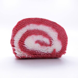 May include: A close-up of a red and white swirl cake roll. The cake is rolled up and has a white filling.