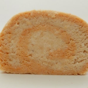 May include: A close-up of a light brown and orange swirl cookie, cut in half to show the inside.