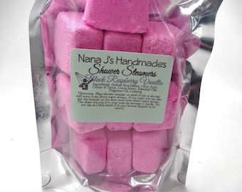 May include: A bag of pink shower steamers with a label that reads "Nana J's Handmades Shower Steamers Black Raspberry Vanilla". The label also includes the ingredients and directions for use.