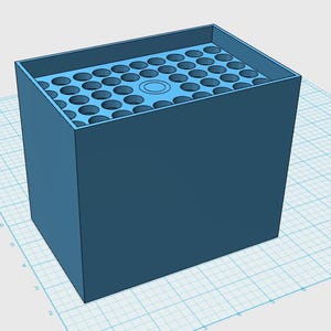 Puede incluir: Un contenedor rectangular azul con una cuadrícula de agujeros circulares en la superficie superior. El contenedor tiene una estructura sólida en forma de caja, con una parte superior ligeramente empotrada. El diseño parece ser un modelo 3D o una representación digital.