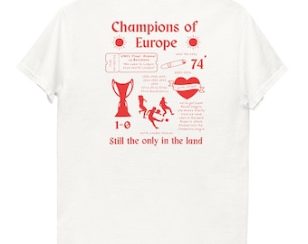 Può includere: T-shirt bianca con un design grafico rosso. Il design include il testo "Champions of Europe", un trofeo, un biglietto, un cuore e il numero "74". La maglietta ha anche il testo "Still the only in the land".