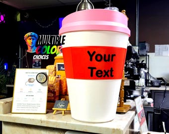 May include: A giant coffee cup with a pink lid and a red band displaying "Your Text." The cup is white with a pink rim. The words "MULTIPLE COLOR CHOICES" are visible in the background.