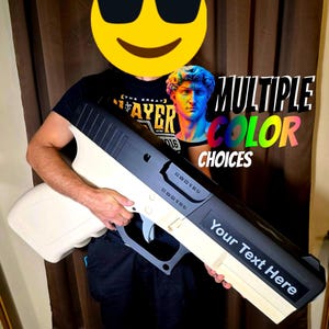 May include: A large, two-tone prop gun with a black top and a cream-colored base. The text "Your Text Here" is visible on the side. The image also includes the text "MULTIPLE COLOR CHOICES".