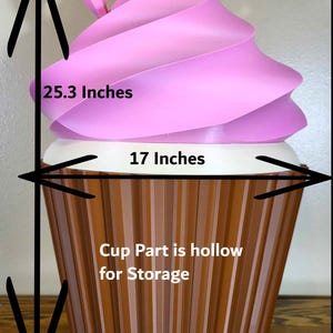 K&ouml;nnte beinhalten: Ein gro&szlig;er dekorativer Cupcake mit rosa Wirbelbelag und einer braunen, gerippten Tasse. Der Cupcake ist 64.3 cm hoch und 43.2 cm breit. Der Becherteil ist zur Aufbewahrung hohl.