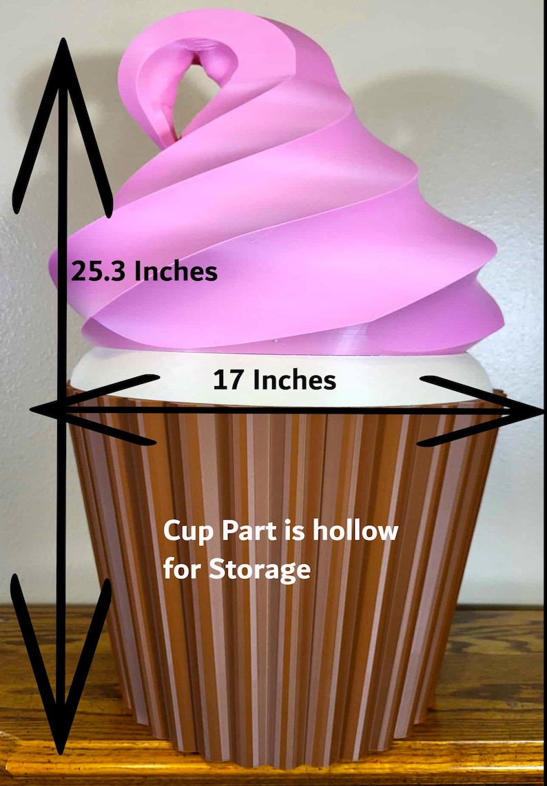 K&ouml;nnte beinhalten: Ein gro&szlig;er dekorativer Cupcake mit rosa Wirbelbelag und einer braunen, gerippten Tasse. Der Cupcake ist 64.3 cm hoch und 43.2 cm breit. Der Becherteil ist zur Aufbewahrung hohl.