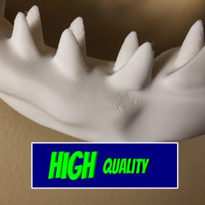 Może przedstawiać: Zbliżenie białej, wydrukowanej w 3D szczęki z ostrymi zębami. Tekst "HIGH QUALITY" w zielonym kolorze na niebieskim tle podkreśla jakość produktu.