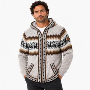 May include: A hooded zip-up sweater in a neutral colour with brown and white geometric patterns and llama designs. The sweater has a front zip, two pockets, and a small patch on the upper right sleeve.