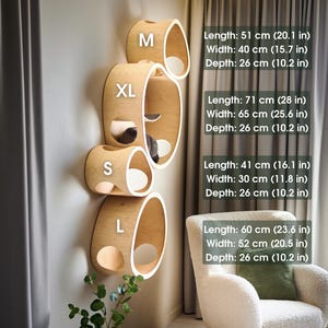 May include: A set of four wooden cat shelves in varying sizes (S, M, L, XL) mounted on a wall. Each shelf has a curved, oval shape with a light wood finish and a white interior. The dimensions are listed in inches and centimeters.
