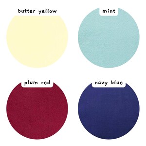 May include: Four circular fabric swatches in butter yellow, mint, plum red, and navy blue. Each swatch features a white rectangular label above it with the corresponding color name printed in black text: butter yellow, mint, plum red, and navy blue.