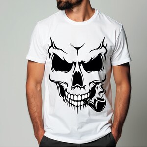 Könnte beinhalten: Weißes T-Shirt mit einem schwarzen Totenkopf-Design, der eine Pfeife raucht. Der Totenkopf hat detaillierte Merkmale, einschließlich scharfer Zähne und intensiver Augen. Die Grafik ist mittig platziert.