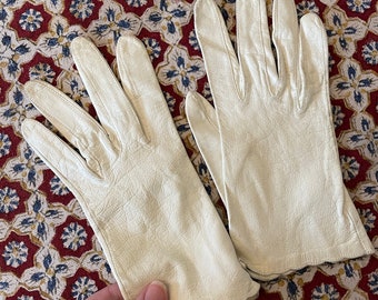 May include: A pair of white leather gloves with a scalloped edge.