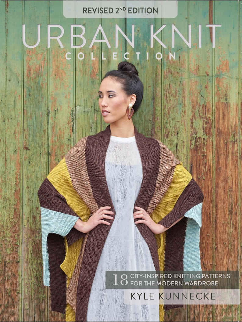 Puede incluir: Una mujer con un chal de punto a rayas en secciones marrones, amarillas y azules. La portada del libro detr&aacute;s de ella dice "Urban Knit Collection" y "Revised 2nd Edition". La portada del libro tambi&eacute;n dice "18 City-Inspired Knitting Patterns for the Modern Wardrobe" por Kyle Kunnecke.